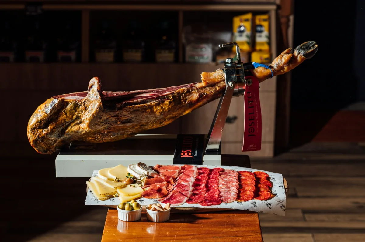 Sliced jamón Ibérico on a wooden board with bread