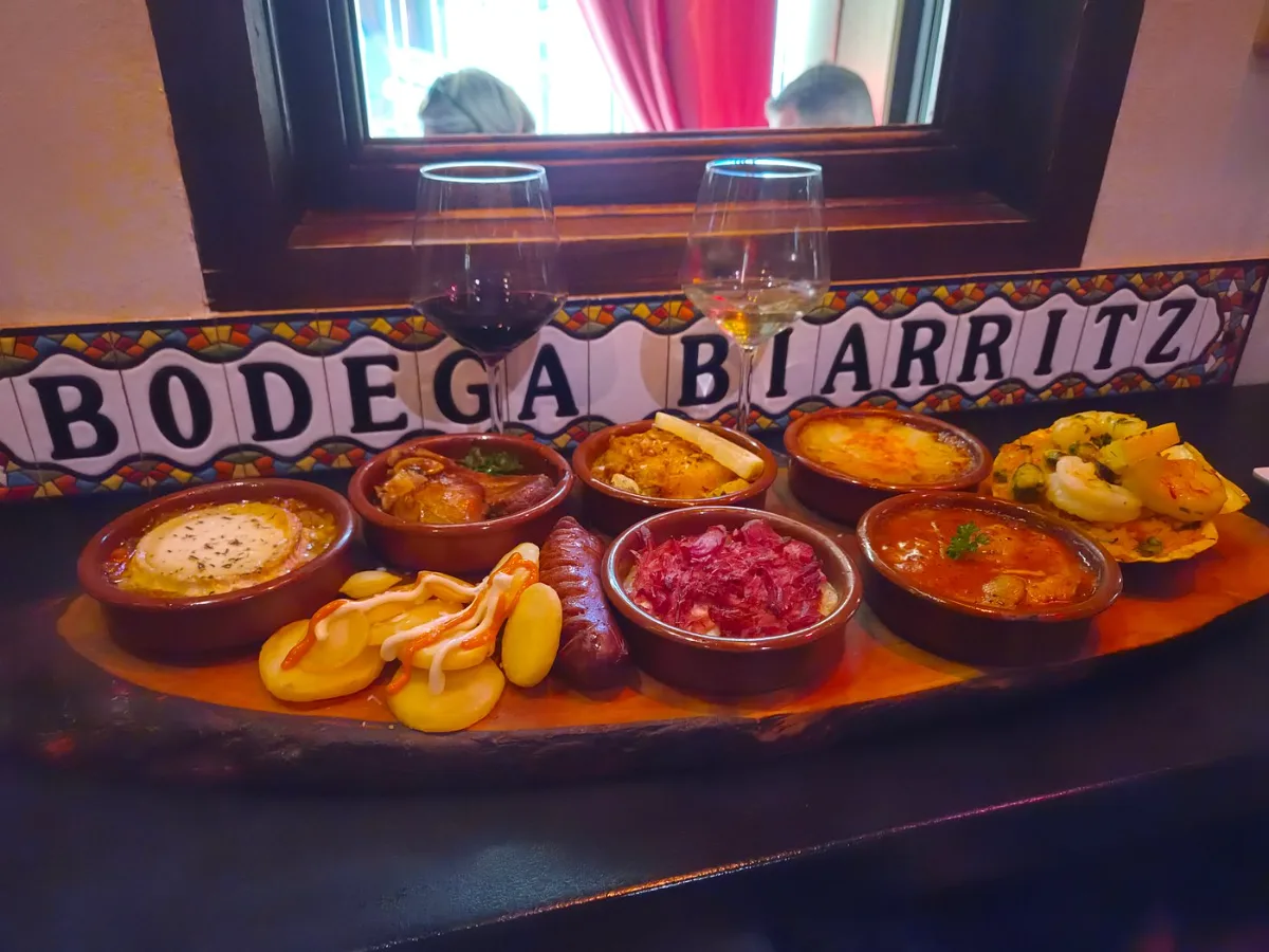 Various Barcelona tapas plates including patatas bravas, jamón, boquerones