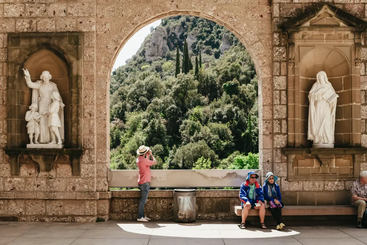 Tourist taking photos at Montserrat monastery with dramatic mountain backdrop