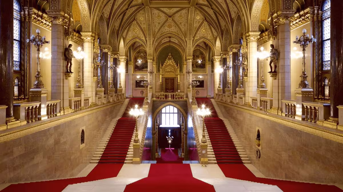 The Grand Stairway inside the Hungarian Parliament Building in Budapest with red carpet and gilded ceiling