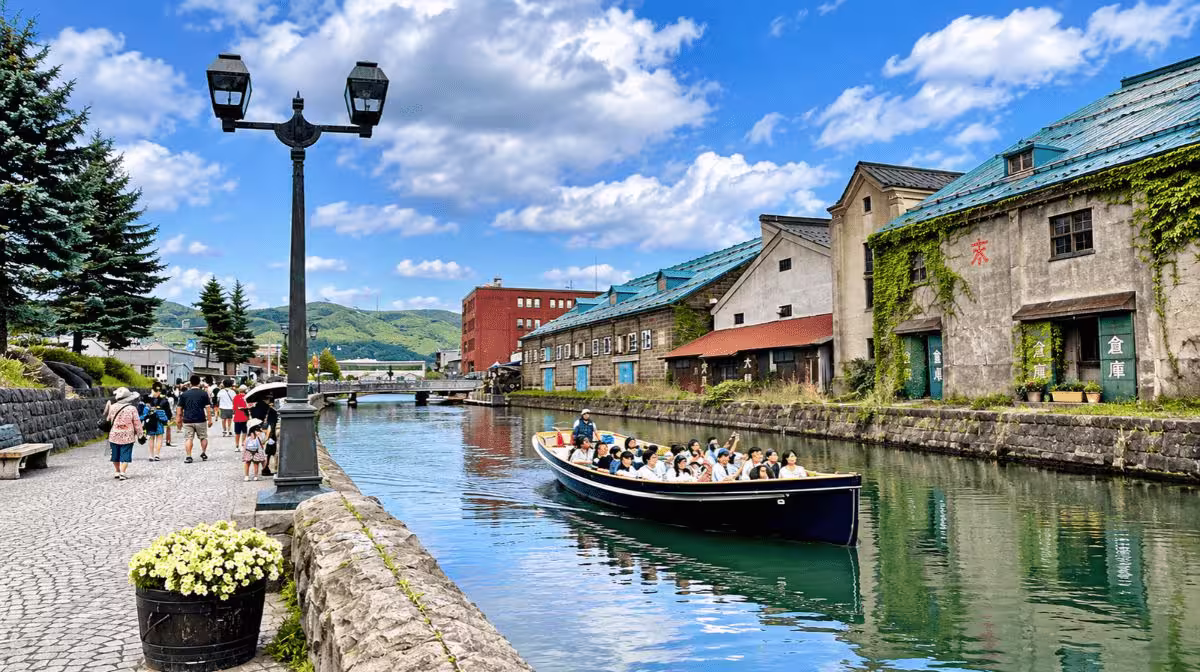 A canal cruise boat passing the stone warehouses and gas lamp along the Otaru Canal