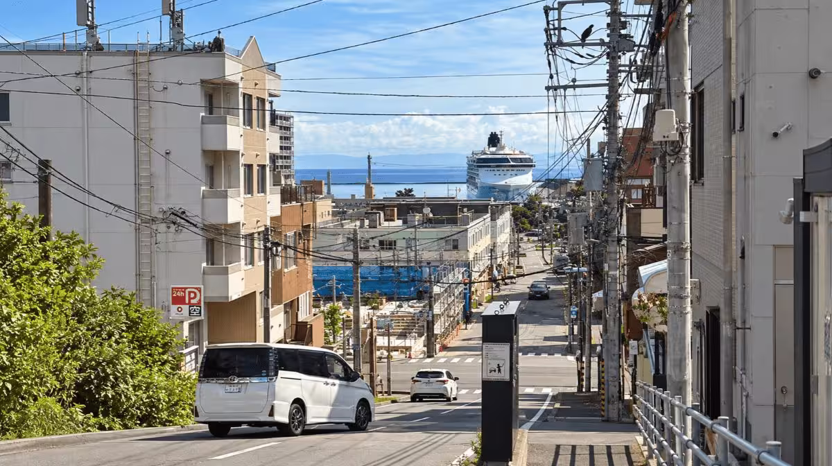 View down the hill toward JR Otaru Station with the cruise ship visible at anchor in the harbor beyond