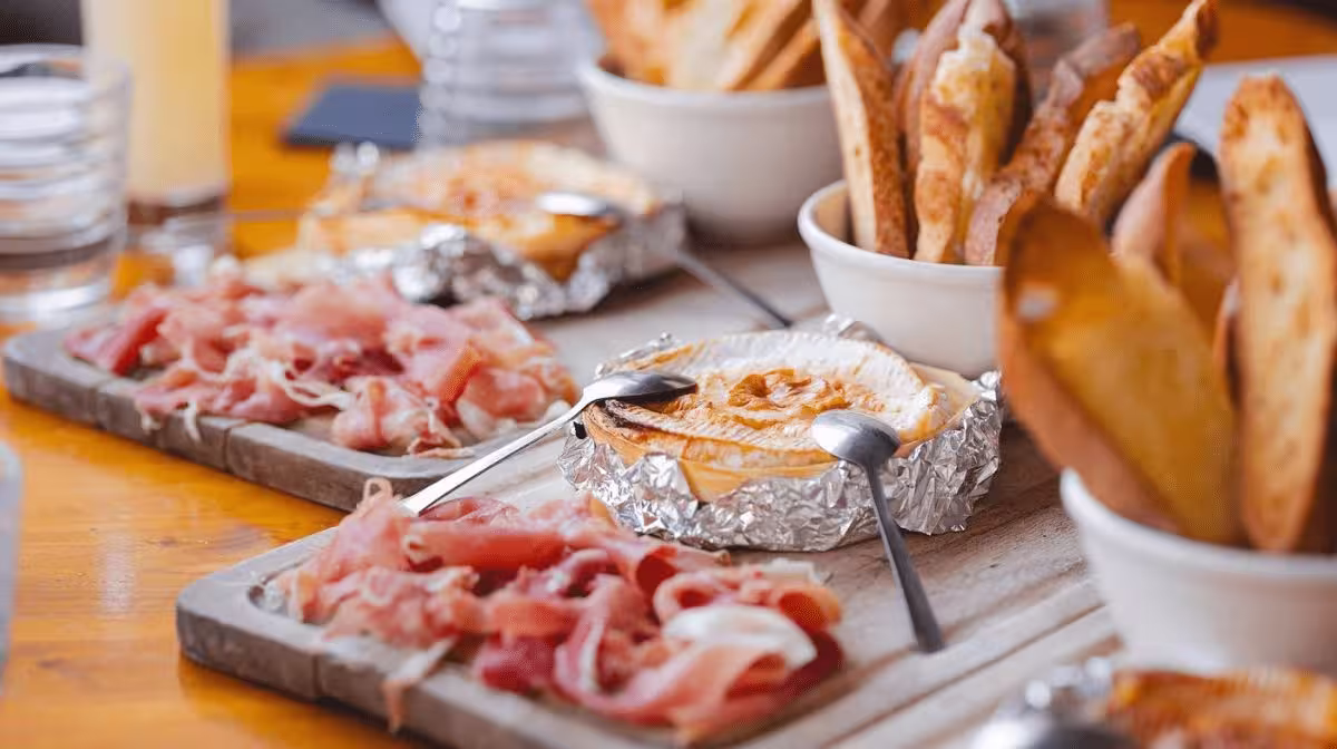 Platter of cured meats, baked cheese and crusty bread at a food tasting in Marseille